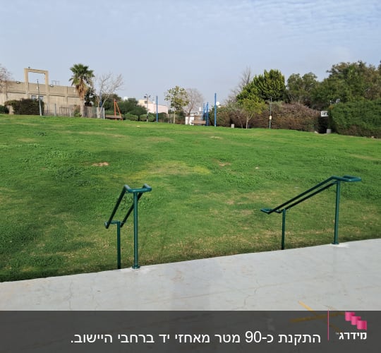 מעקה מתכת על מדרכה מול מדשאה ירוקה